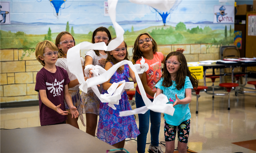 A group of students try to catch paper that is being blown around